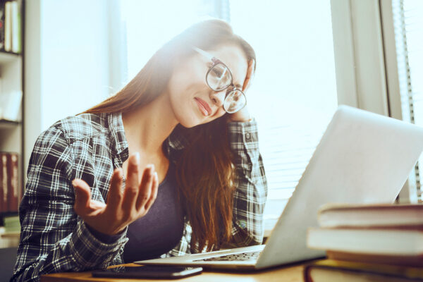 Stressed Student with eyeglasses Doing Homework in library